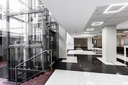 Modern hallway with glass elevator Architect